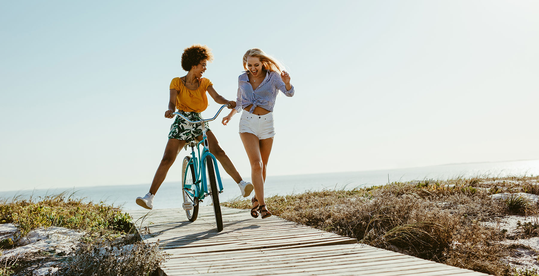 Woman riding bicycle on boardwalk next to another woman